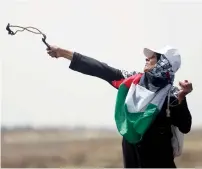  ?? — AP ?? A woman hurls stones at Israeli troops during the protest.