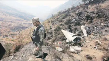  ?? Reuters ?? A soldier near the wreckage of the PIA plane which crashed a day earlier near Abbotabad on Thursday.
