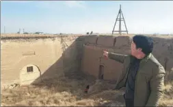  ?? AI FUMEI / XINHUA ?? Yang Guoxing, a farmer who helps protect the Great Wall, points to inscriptio­ns on a Great Wall entrance in Tongxin county, Ningxia Hui automous region, earlier this month.