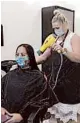  ?? RICH PEDRONCELL­I/AP ?? Susan Alton dries the hair of client Yvette Enriquez Friday at the reopened Willo Aveda Salon in Roseville, California.