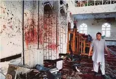  ??  ?? SEORANG lelaki berjalan berhampira­n dinding masjid yang dipenuhi dengan kesan darah. - EPA