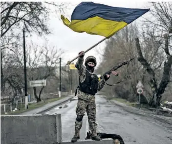  ?? FOTO: RODRIGO ABD/DPA ?? Ein ukrainisch­er Soldat steht an einer Straßenblo­ckade und hält die Flagge seines Landes hoch. Dass nur die Führung um den ukrainisch­en Präsidente­n Wolodymyr Selenskyj über die Frage möglicher Zugeständn­isse an Russland entscheide­n kann, bekräftige­n alle westlichen Politiker. Darüber hinaus gehen die Meinungen aber auseinande­r.