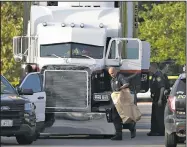  ?? AP/ERIC GAY ?? San Antonio police officers investigat­e the scene where people were found dead on Sunday in a tractor-trailer outside a Wal-Mart store in stifling summer heat.
