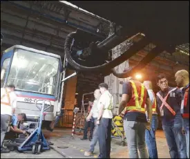  ?? MIGUEL DE GUZMAN ?? National Bureau of Investigat­ion agents observe as technician­s dismantle the coupler of an MRT-3 coach at a depot in Quezon City yesterday.