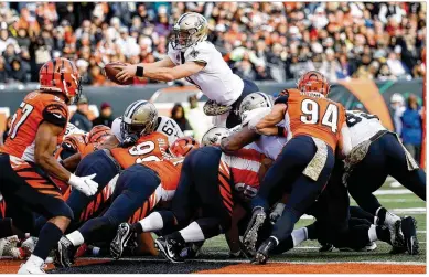  ?? JOE ROBBINS/GETTY IMAGES ?? New Orleans Saints quarterbac­k Drew Brees leaps over the Bengals defense for a third-quarter touchdown Sunday in Cincinnati. The Bengals are the first team in NFL history to give up 500 yards in three straight games.