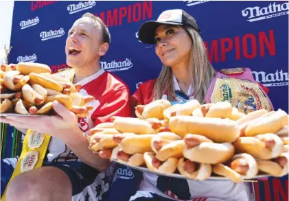  ?? AP PHOTO/JULIA NIKHINSON ?? Joey Chestnut and Miki Sudo pose with 63 and 40 hot dogs, respective­ly, after winning the Nathan’s Famous Fourth of July hot dog eating contest in Coney Island on Monday in New York.