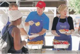  ?? ALEX BRANDON/ AP ?? Supreme Court nominee Brett Kavanaugh ( center) serves macaroni and cheese to homeless people as he volunteers with Catholic Charities on Wednesday in Washington, D. C.