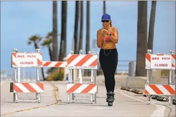 ?? Gary Coronado Los Angeles Times ?? TO SLOW THE spread of the coronaviru­s, many Southern California cities have closed beach access for the normally busy Fourth of July weekend. Above, a woman skates along a bike path Friday in Manhattan Beach.