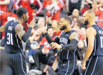  ?? JOE BURBANK/ORLANDO SENTINEL ?? Orlando Magic guard D.J. Augustin, center, is congratula­ted by teammates Terrence Ross (31) and Evan Fournier after Augustin hit the game-winning shot against the Raptors in the first round of the NBA playoffs Saturday in Toronto.