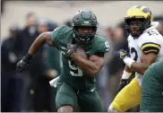  ?? AP ?? Michigan State’s Kenneth Walker III (9) rushes against Michigan’s Josh Ross during the first quarter on Saturday in East Lansing, Mich.