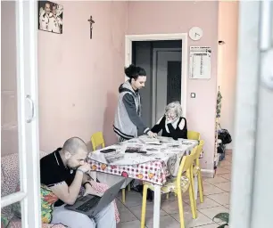  ??  ?? Antoine Khoury helps his mother Maha Dahine study Italian while brother Hanna Khoury works on a laptop in their apartment in Pinerolo, Italy, after they fled Syria and previously spent two years in Lebanon.