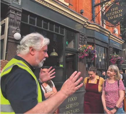  ?? AP PHOTO ?? Writer and tour guide Nick Hennegan leads a group of tourists through London’s Fitzrovia area to explore pubs connected to famous writers.