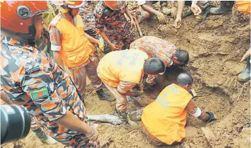  ?? — AFP photo ?? Bangladesh­i firefighte­rs try to recover a body at the site of a landslide in Rangamati.