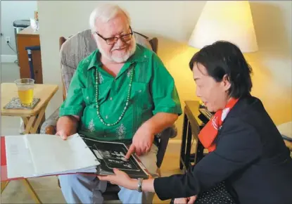  ?? RENA LI / CHINA DAILY ?? Lee Gardner (left) shows photograph­s of his family in Kuliang to Guo Ningning, vice-governor of Fujian province, in El Segundo, California, in the United States, on March 17.