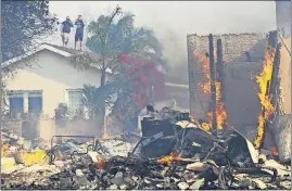  ?? [JAE C. HONG/THE ASSOCIATED PRESS] ?? Two residents watch from a rooftop as a home burns in a wildfire in Ventura.