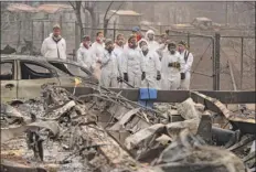  ?? John Locher / Associated Press ?? Anthropolo­gy students observe as human remains are recovered Sunday from a burned-out home in Paradise, Calif. the northern California blaze has killed at least 23 people.