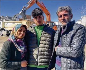  ?? MEHMET MUCAHIT CEYLAN/AP ?? Taha Erdem, 17, is embraced by his mother, Zeliha, and father, Ali, next to the destroyed building where they were trapped under separate piles of concrete when their home collapsed in the earthquake in Adiyaman, Turkey. They survived after being dug out by family and volunteers.