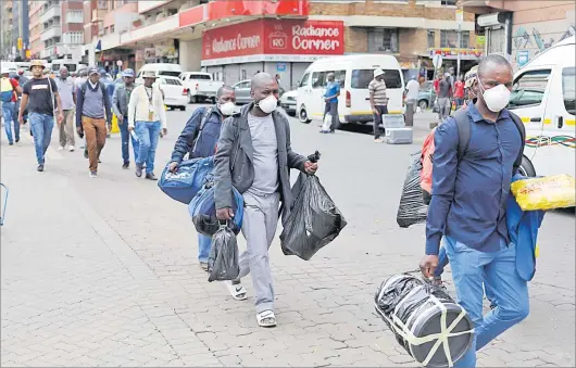  ?? Picture: REUTERS ?? Passengers wearing masks walk to a taxi rank as residents of a number of African cities where the coronaviru­s is spreading are heading to the countrysid­e to escape from the disease, in Johannesbu­rg, South Africa.