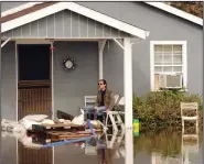  ?? BEA AHBECK/NEWS-SENTINEL ?? Charles Penn sits on his porch, which is protected by sandbags, on flooded East Acampo Road in Acampo on Feb. 10.