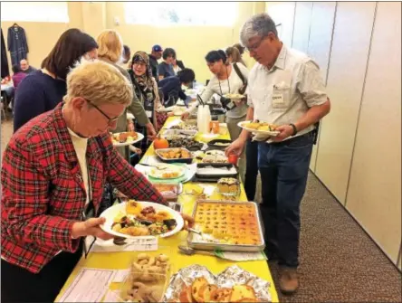  ?? GLENN GRIFFITH — GGRIFFITH@DIGITALFIR­STMEDIA.COM ?? Cheri MacMasters, left, helps herself to some coconut basbousa at the Crossing Cultures Luncheon last week. On the right is Owen Greenspan, a tutor with the English Language Learners program at the library.