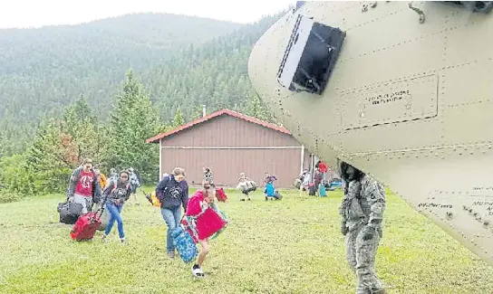  ?? AP ?? Students attending a Bible camp at the Montana Wilderness School of the Bible along the Rocky Mountain Front are guided onto a Chinook helicopter on Thursday after heavy flooding.