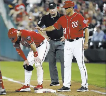  ?? Alex Brandon The Associated Press ?? Nationals first-base coach Tim Bogar tends to Bryce Harper after the Las Vegas native was hit by a pitch in the sixth inning of Washington’s 6-2 win over the Reds.