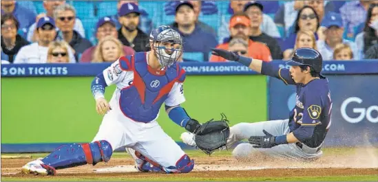  ?? Gina Ferazzi Los Angeles Times ?? MILWAUKEE RIGHT FIELDER Christian Yelich beats out a throw to Dodgers catcher Yasmani Grandal to score on a first-inning double by left fielder Ryan Braun.