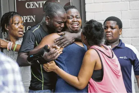  ?? Elizabeth Conley / Staff photograph­er ?? The mother of two young children, a 1-year-old girl and an 8-year-old boy, is comforted by her family after she found their bodies in their father’s apartment on Saturday. Police are searching for the suspect’s black 2008 Nissan Titan.