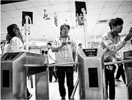  ?? QILAI SHEN/BLOOMBERG NEWS ?? Employees look into facial recognitio­n devices and swipe their badges to enter the assembly line area at a Pegatron factory in Shanghai, China. Concerns are growing over the possible bias that facial recognitio­n brings.