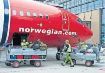  ??  ?? Personal de servicios junto a un avión de Norwegian.