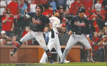  ?? The Associated Press ?? BRAVES ROAR: Atlanta Braves’ Dansby Swanson, left, and Rafael Ortega, right, celebrate after scoring Sunday as St. Louis Cardinals relief pitcher Carlos Martinez (18) walks in the background during the ninth inning in Game 3 of the National League Division Series in St. Louis.