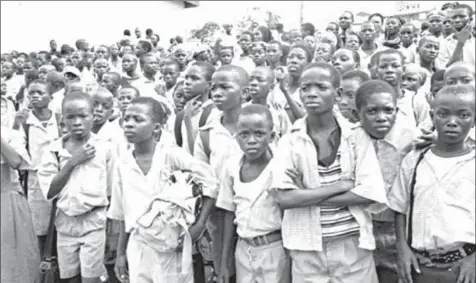  ??  ?? A cluster of pupils listening to an address in school