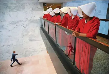  ?? WIN MCNAMEE / GETTY IMAGES ?? Protesters, dressed in “The Handmaid’s Tale” costumes, outside the Senate hearing room where Supreme Court nominee Brett Kavanaugh testified. The handmaids, who wear red robes and white bonnets in the TV adaptation of the dystopian novel by Margaret Atwood, have inspired real-life political activism to oppose policies that restrict abortion and health care for women.