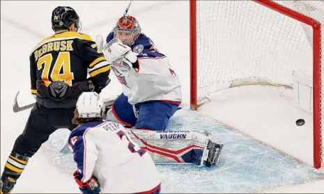  ?? Michael Dwyer / Associated Press ?? The Bruins’ Jake DeBrusk (74) watches the goal by David Pastrnak get past Blue Jackets’ goalie Daniil Tarasov, right, during the first period Saturday in Boston. Boston improved to 16-0-2 at home with the win.