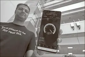  ?? Hayne Palmour IV/The San Diego Union-Tribune/TNS, File ?? Senior Staff Engineer Vid Adiraju holds a smartphone as it goes through a 5G speed test, which shows that it has reached the level of 5G, with two commercial-grade 5G millimeter network antenna boxes, background right, at the Qualcomm headquarte­rs in San Diego, California.