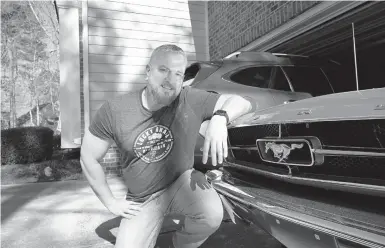  ?? ALLEN G. BREED/AP ?? Steve Bock kneels beside his 1965 Ford Mustang at his home in Apex, North Carolina. He recently bought a Subaru Outback, but would like to have an electric or hybrid car if they were cheaper. Electric vehicles make up less than 2% of new vehicle sales in the U.S.