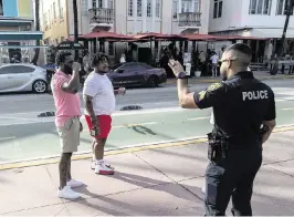  ?? JOSE A. IGLESIAS jiglesias@elnuevoher­ald.com ?? Sergeant Fernandez of the Miami Beach Police Department, right, advises two men walking along Ocean Drive on Thursday that drinking alcohol in open containers is not allowed in Miami Beach.