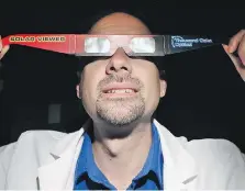  ??  ?? Dr. Brian Blake displays specially designed glasses that allow the safe viewing of a solar eclipse.