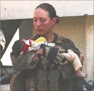  ?? Department of Defense via Associated Press ?? This undated photo provided by U.S. Department of Defense Twitter page posted Aug. 20 shows Sgt. Nicole Gee holding a baby at Hamid Karzai Internatio­nal Airport in Kabul, Afghanista­n. Officials said Saturday that Sgt. Nicole Gee, of Sacramento, Calif., was killed in Thursday’s bombing in Kabul.