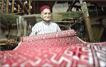  ?? FADEL SENNAI/AFP ?? Abdelkader Ouazzani, the last of Morocco’s brocade master weavers, displays tapestry at his workshop in the old city of Fez.