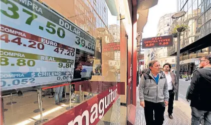  ?? MAXI FAILLA ?? Cayó 50 centavos. Los transeúnte­s observan las pantallas en las casas de cambio.