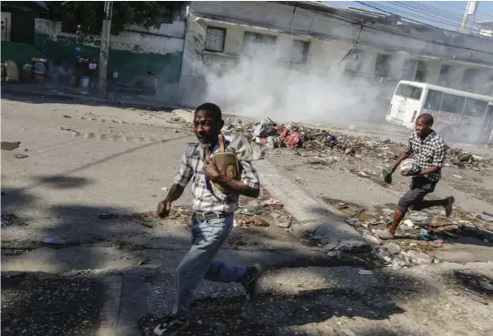  ?? BILD: ODELYN JOSEPH ?? Män springer för att ta skydd från polisens tårgas i centrala Port-au-prince den 2 april.