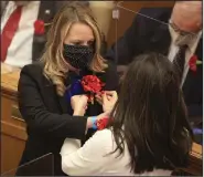  ?? (Arkansas Democrat-Gazette/Staton Breidentha­l) ?? Reps. Megan Godfrey (left), D-Springdale, and Nicole Clowney, D-Fayettevil­le, help each other Monday in pinning red carnations to their lapels, a tradition for the first day of the legislativ­e session.