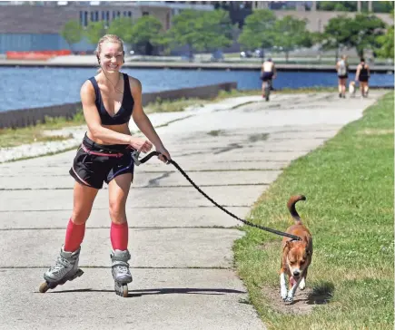  ?? ANGELA PETERSON / MILWAUKEE JOURNAL SENTINEL ?? Kathryn Minster, 24, of Mequon enjoys roller blading with her 2-year-old dog, Shelly, on Thursday at the Milwaukee lakefront. Areas right along the Great Lakes are forecast to be the only places in Wisconsin where some relief might be found as a heat wave takes hold across much of the state in the next week.