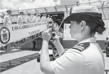  ?? Stuart Villanueva / Associated Press ?? Navy Lt. Miranda Williams photograph­s sailors as they board the USS Gabrielle Giffords during a commission­ing ceremony in Galveston. The Navy announced it now will let female sailors have ponytails and other longer hairstyles.