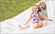  ?? CAROLE MORRIS-UNDERHILL ?? Children laughed and smiled as they made their way down the firefighte­r-run water slide at the Falmouth Community Hall June 16. The event was part of the annual Teddy Bear Jamboree. Pictured are Emma and Kayla Cooper, of Falmouth.