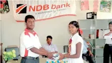  ??  ?? NDB Vavuniya Branch staff member T. Surendran, giving away LED Lamp to a student of the Karuveppan­kulam GTMS in Kidachuri, Vavuniya.