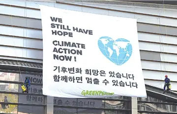  ?? — AFP photo ?? Greenpeace activists display a big banner reading ‘We still have hope, Climate action now!’ during an activity prior to a press conference of the Intergover­nmental Panel for Climate Change (IPCC) at Songdo Convensia in Incheon.