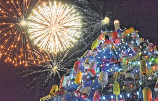  ?? KATHY JOHNSON PHOTOS ?? Fireworks light up the night sky behind the Municipali­ty of Barrington's lobster pot Christmas during one of the annual community tree lighting events.