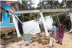  ?? (Foto Nik Abdullah Nik Omar/bh) ?? Penduduk melihat keadaan rumah yang rosak teruk akibat banjir di Kampung Telaga Bata, Tumpat, baru-baru ini.